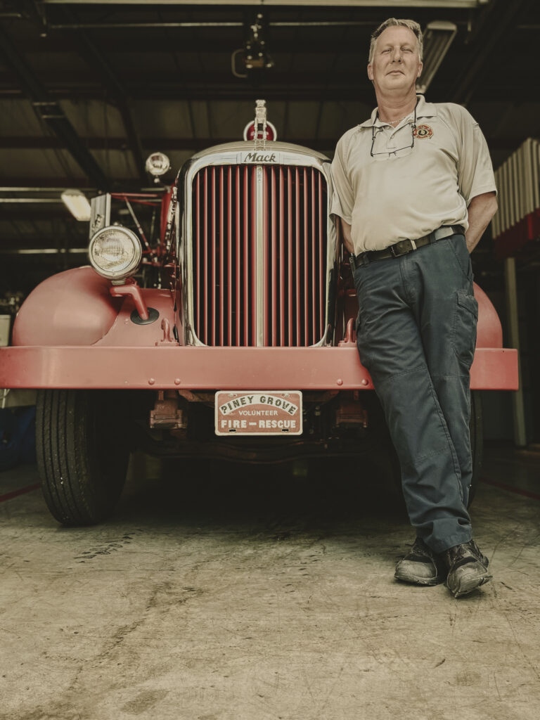 Chief Carl Walker standing in front of a vintage Piney Grove Volunteer Fire-Rescue truck